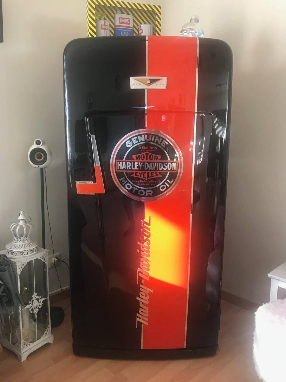 Schwarzer Kühlschrank mit Harley-Davidson-Logo und rotem Streifen in einem Zimmer.