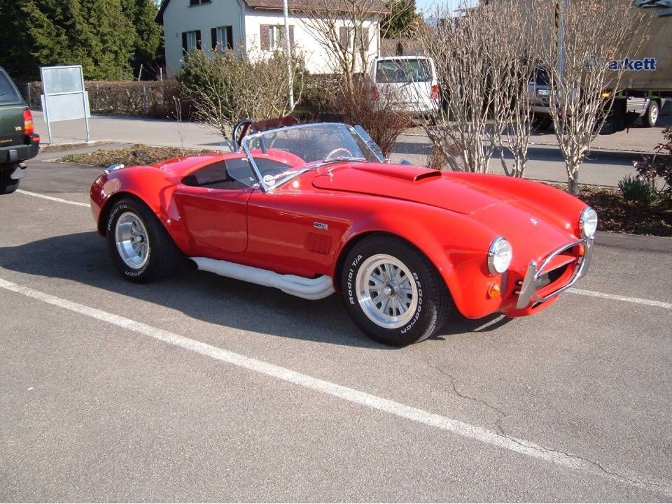 Ein roter AC Cobra Sportwagen steht im Freien.