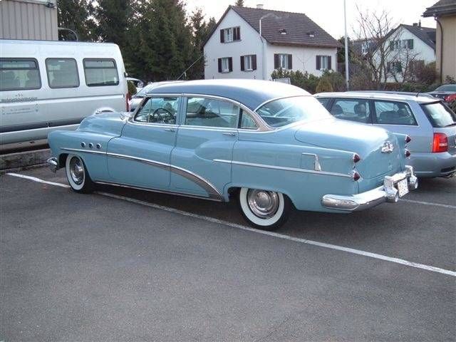 Hellblauer Oldtimer-Buick, weisse Reifen, im Hintergrund Häuser.
