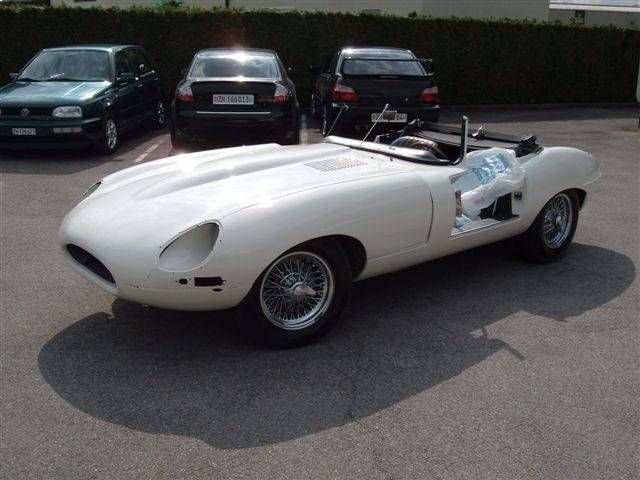 Weisser klassischer Jaguar E-Type Roadster, auf einem Parkplatz abgestellt, Karosserie teilweise demontiert.