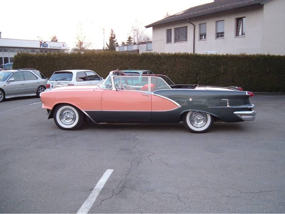 Ein zweifarbiges Cabriolet in Koralle und Türkis mit Weisswandreifen steht auf einem Parkplatz.