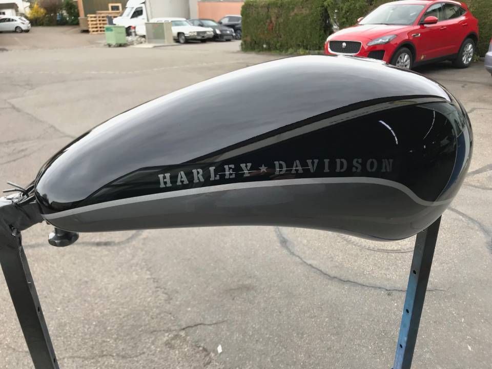 Schwarzer und silberner Benzintank einer Harley-Davidson, auf einem Ständer im Freien.