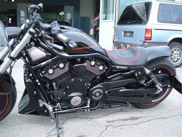 Schwarzes Harley-Davidson-Motorrad mit roten Zierelementen, draussen neben einem Lieferwagen geparkt.