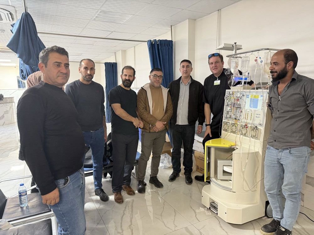 Eine Gruppe von Männern steht in einem Krankenzimmer neben einem medizinischen Gerät.