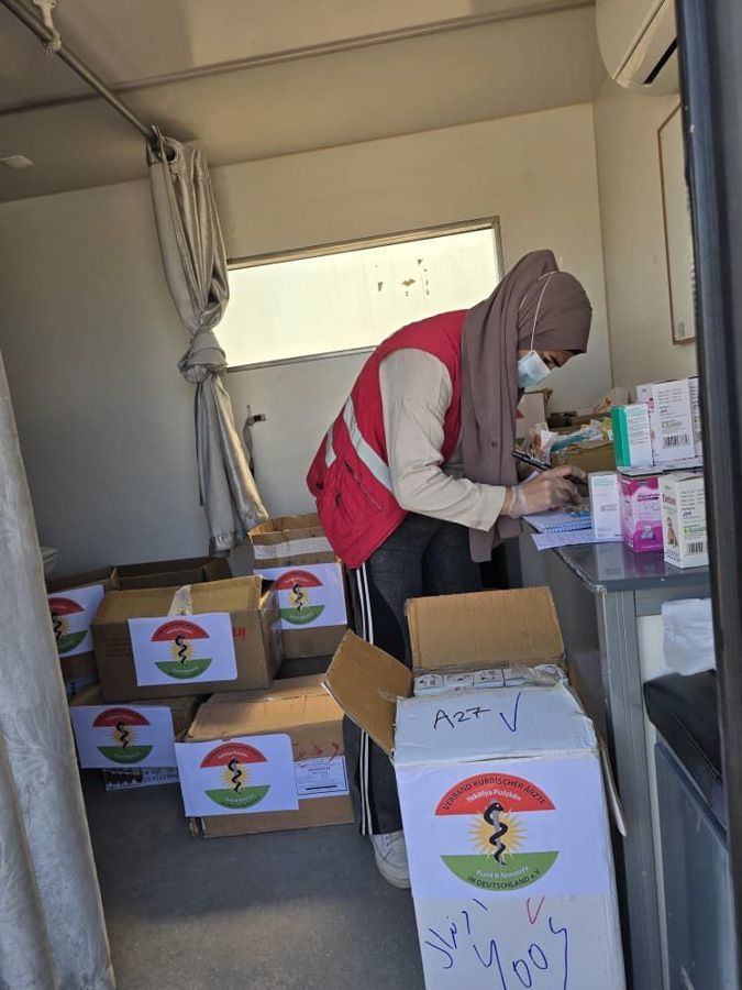 Freiwillige verladen Hilfsgüter in einen LKW, auf dem Kisten gestapelt und Spendenartikel auf einem Tisch bereitgestellt werden.