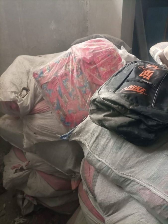 In einem Lagerraum gestapelte Säcke mit Getreide oder Futtermitteln, mit Plastikfolie abgedeckt, darauf schwarze, verpackte Waren.