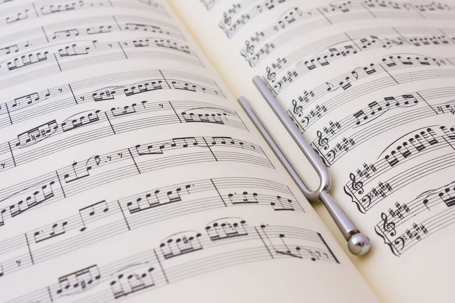 Libro de partituras abierto con un diapasón apoyado sobre una página.