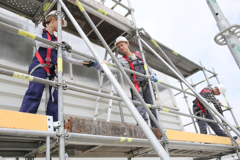 Gerüst an einer Baustelle Arbeiter in Schutzausrüstung auf einem Gerüst an einer Baustelle