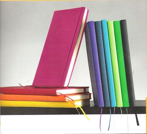 Un libro rosa se encuentra encima de una pila de libros coloridos.