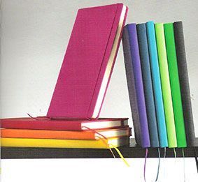 Una pila de cuadernos de colores en un estante.