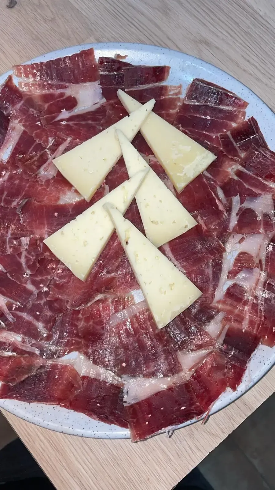Plato de jamón curado en lonchas finas con cuñas triangulares de queso.