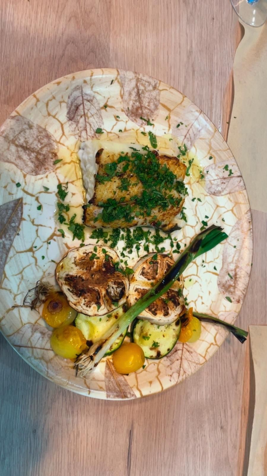 Pescado a la parrilla con verduras en un plato decorativo.