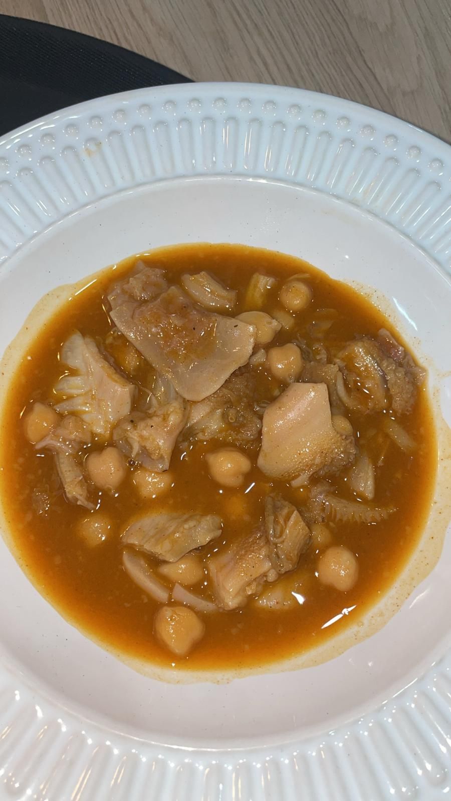 Cuenco de guiso de callos con garbanzos en cuenco blanco estampado.