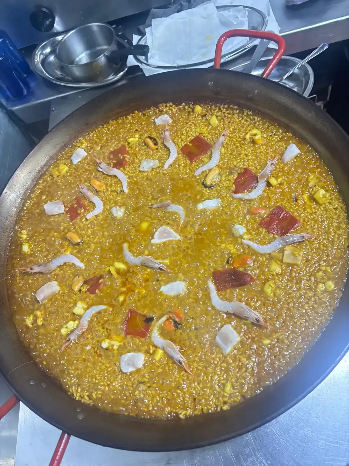 Paella en sartén redonda, con marisco y verduras.