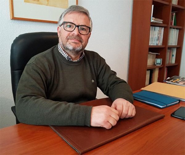 Un hombre con un suéter verde se sienta en un escritorio.