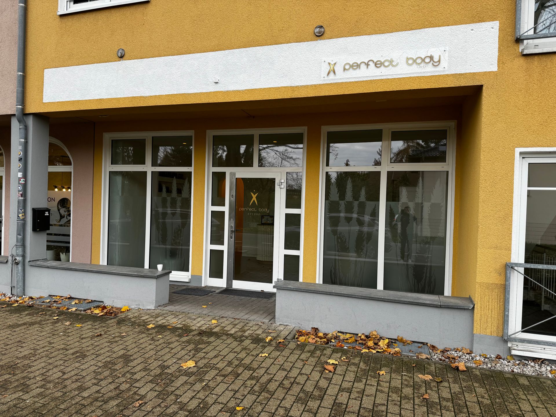 Ein gelbes Gebäude mit einem weißen Schild mit der Aufschrift „x Perfect Body“.