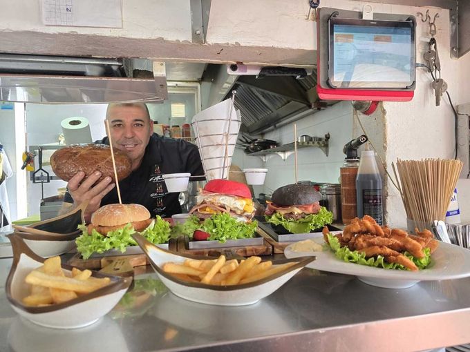 Chef cocinando comida en una sartén sobre la llama de una estufa de gas con una cuchara de madera.