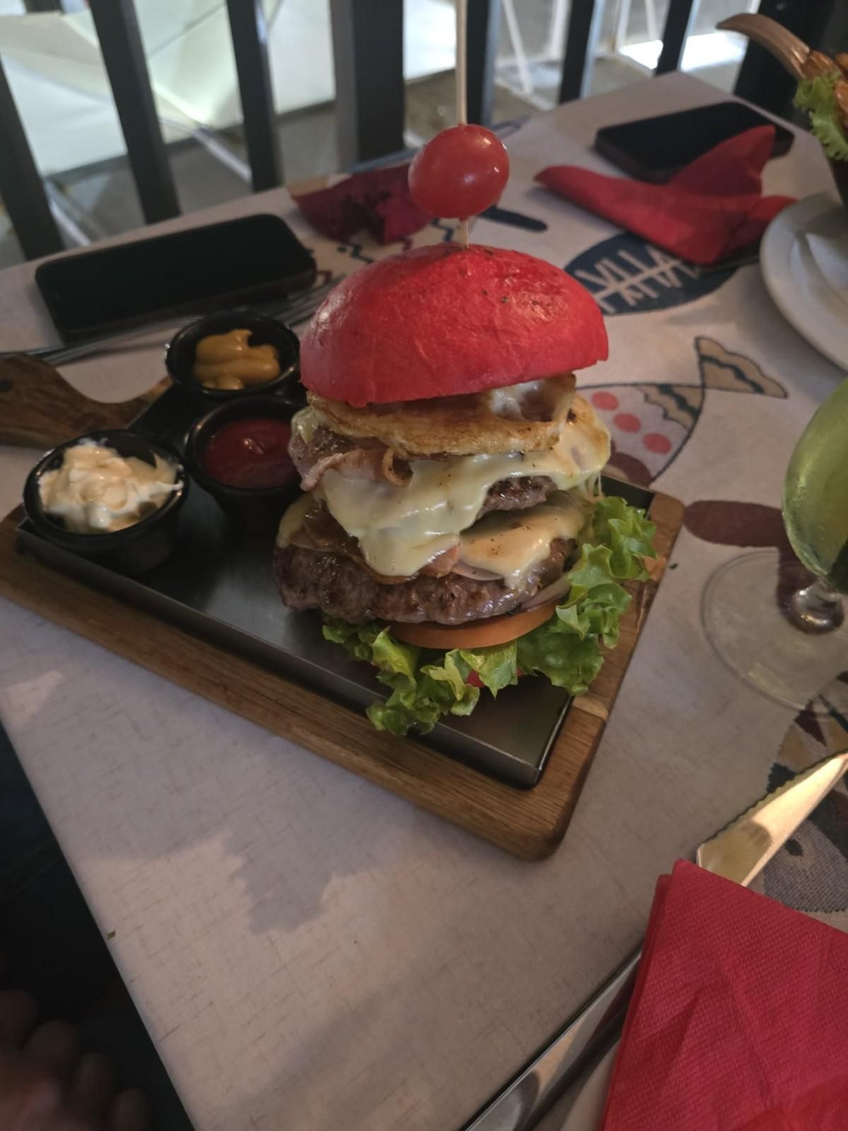 Bistec a la parrilla con patatas fritas y pimientos verdes en un plato negro, sobre una tabla de madera.