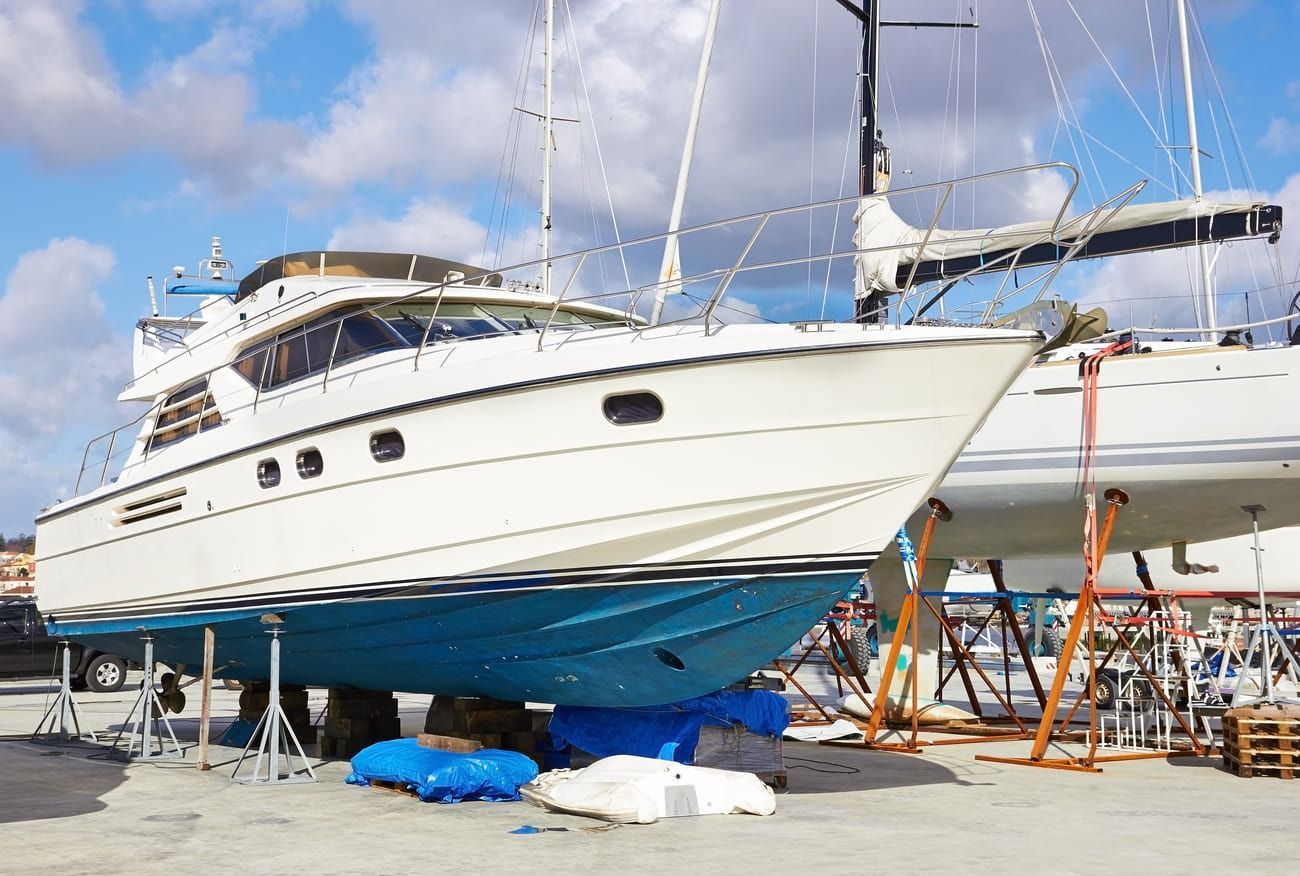 Un barco blanco está sentado encima de un barco azul en un puerto deportivo.