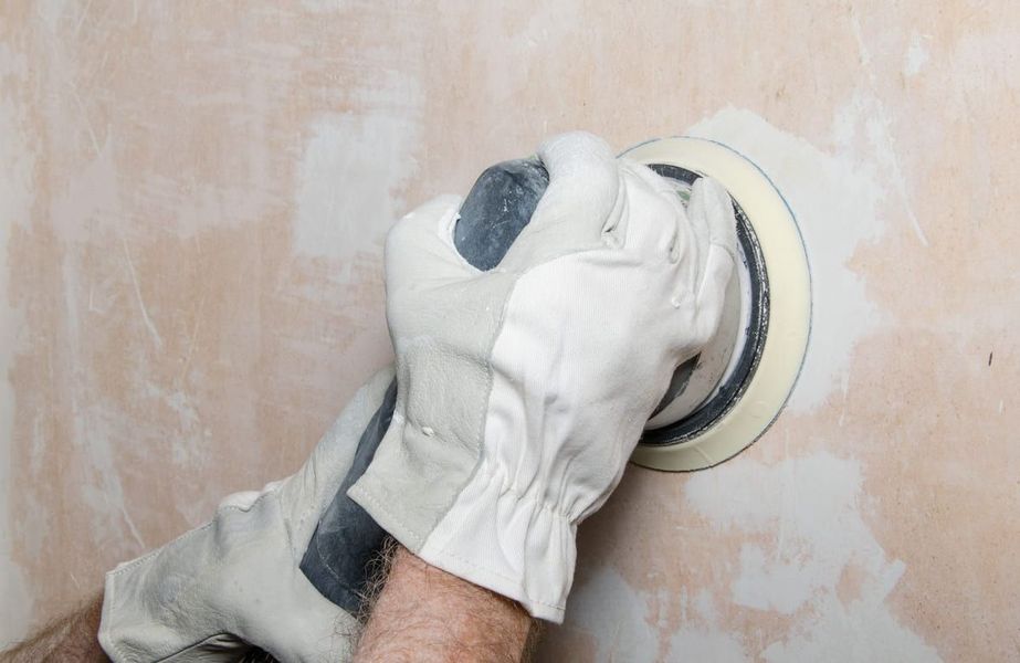Una persona está lijando una pared con una lijadora.