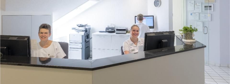 Zwei Assistentinnen sitzen am Tresenvon der Praxis Walter A. Aeschbacher