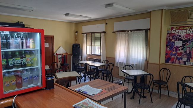 Una habitación con mesas y sillas y un refrigerador de Coca Cola.