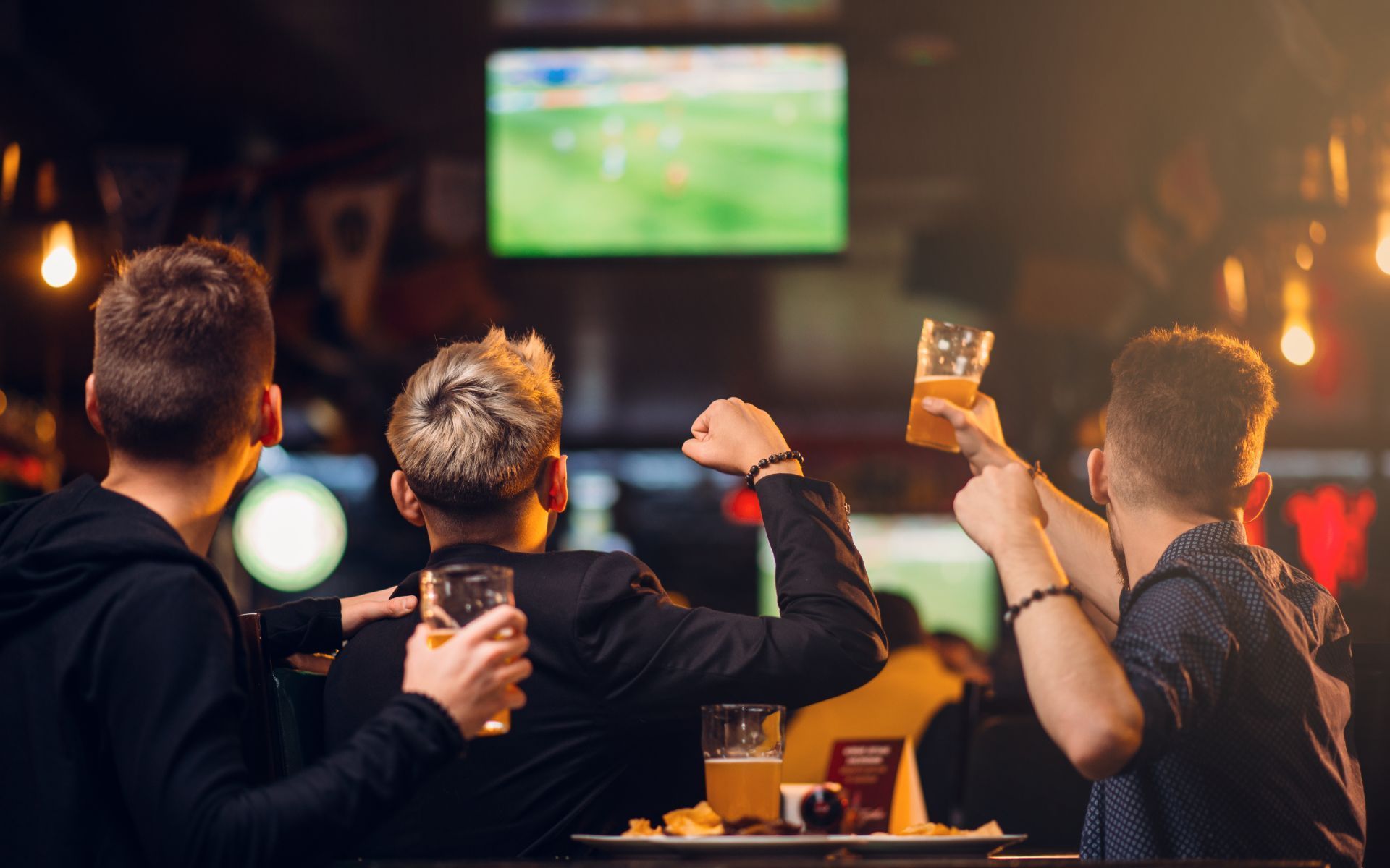 Un grupo de jóvenes está viendo un partido de fútbol en un bar.