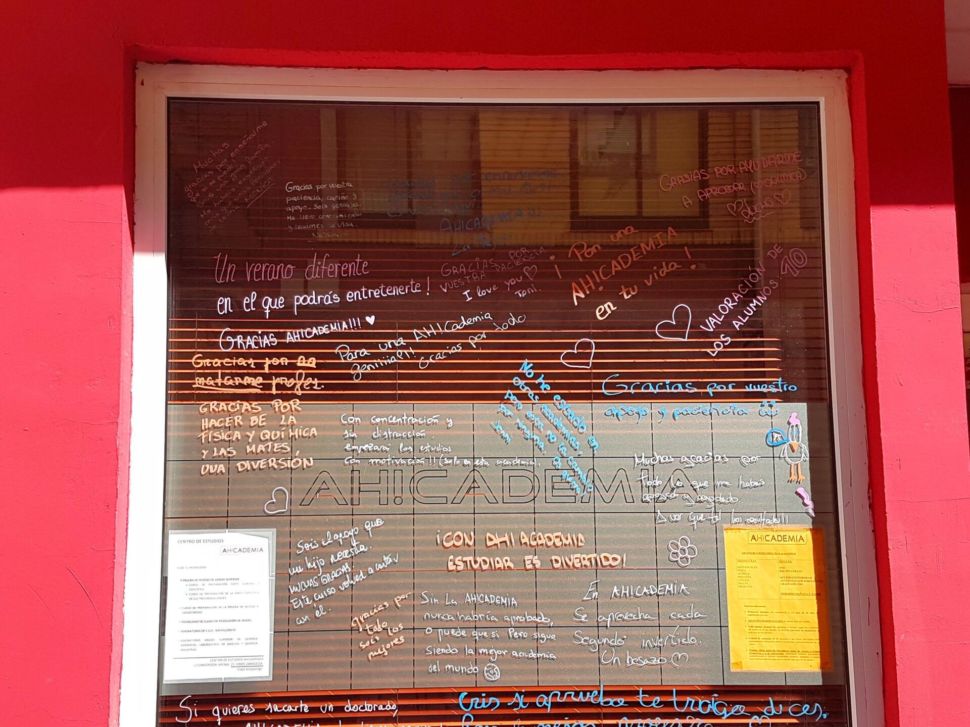 Pared roja con una ventana que presenta numerosas notas escritas a mano en el cristal.