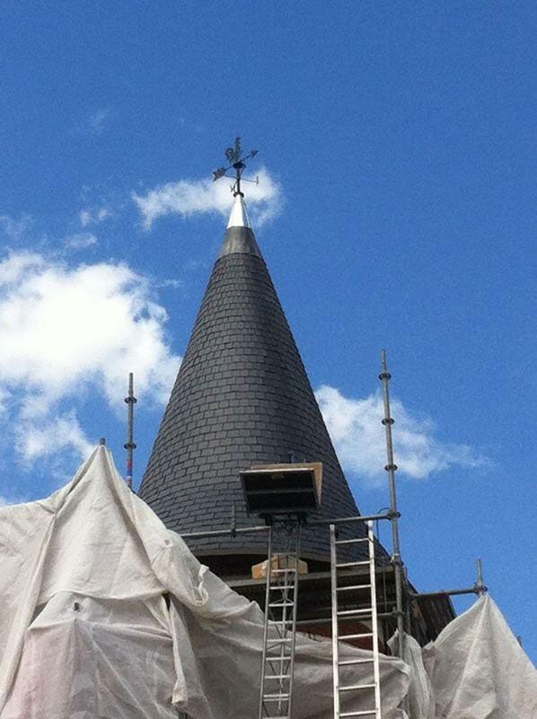 Pose d'une girouette en haut d'une tour au toit en ardoises