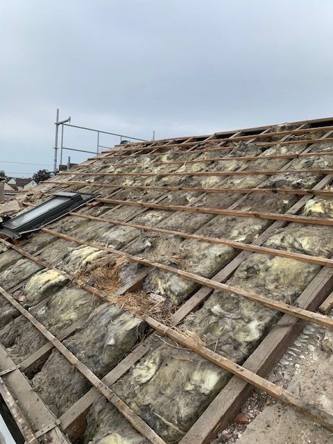 Tuiles enlevées laissant l'isolant visible sur le toit