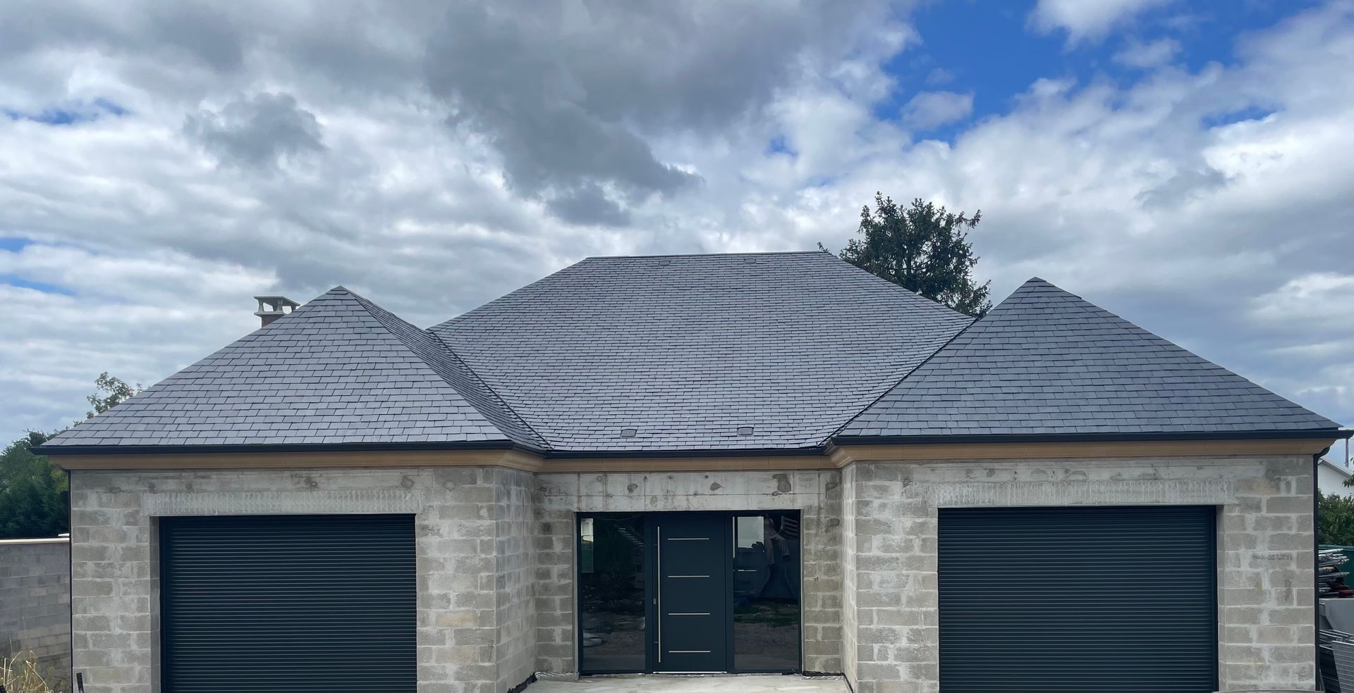 Maison en brique grise avec un toit en ardoise