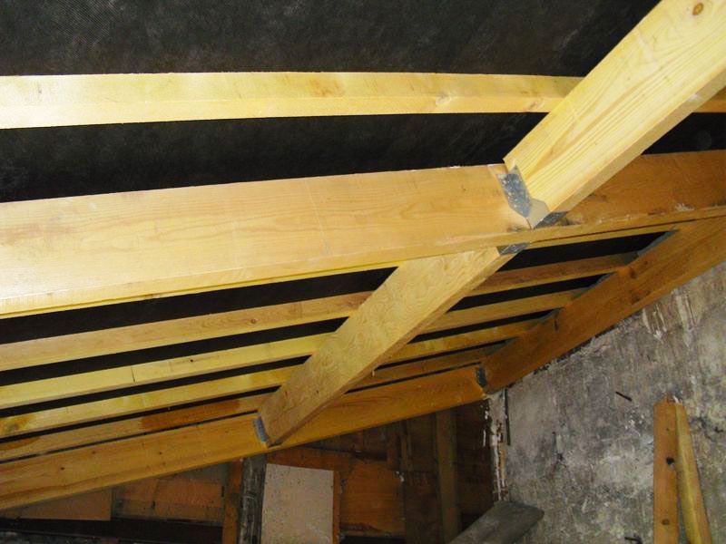 Charpente de maison en bois sous une bâche noire