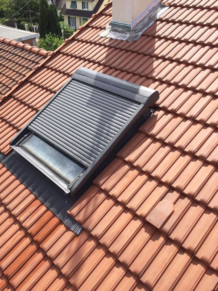Fenêtre de toit avec volet roulant fermé sur un toit en tuiles