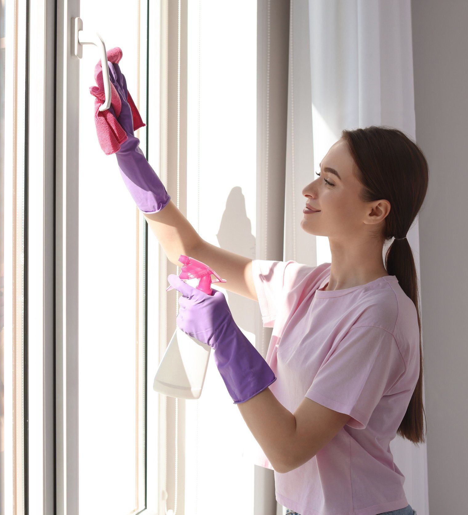 Una mujer que lleva guantes morados está limpiando una ventana.