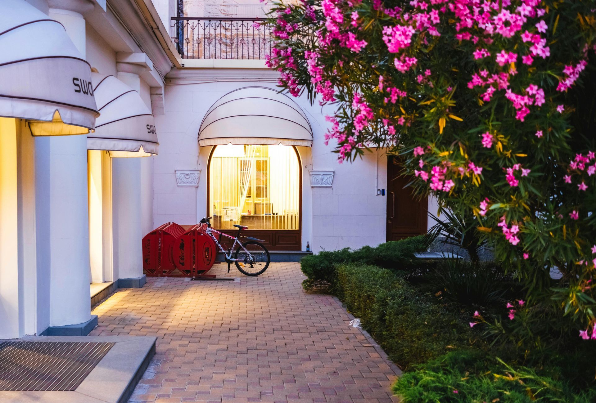 Una bicicleta está estacionada frente a un edificio con flores rosas.