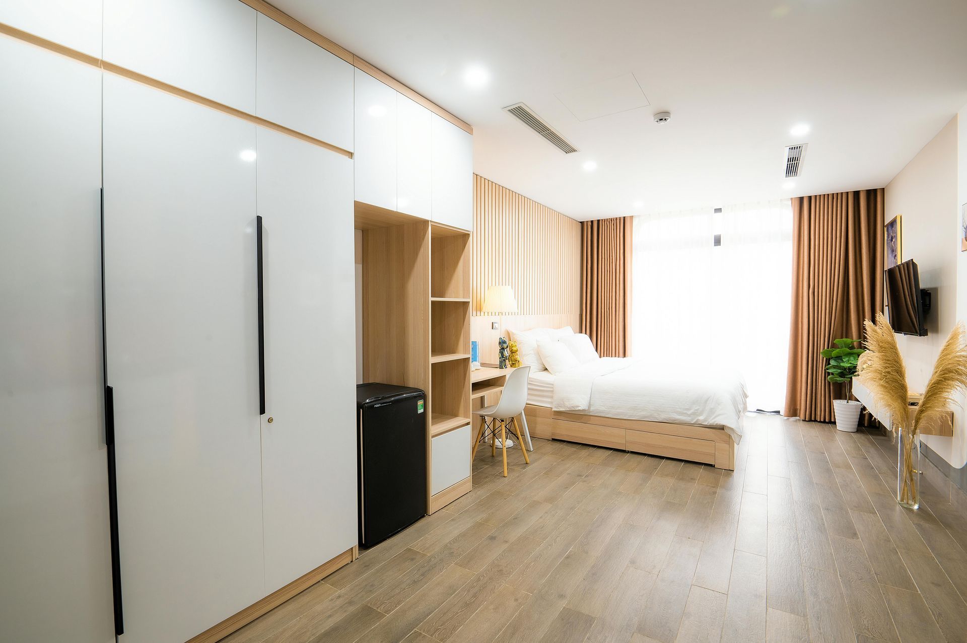 Una habitación de hotel con una cama, un escritorio, armarios y un refrigerador.