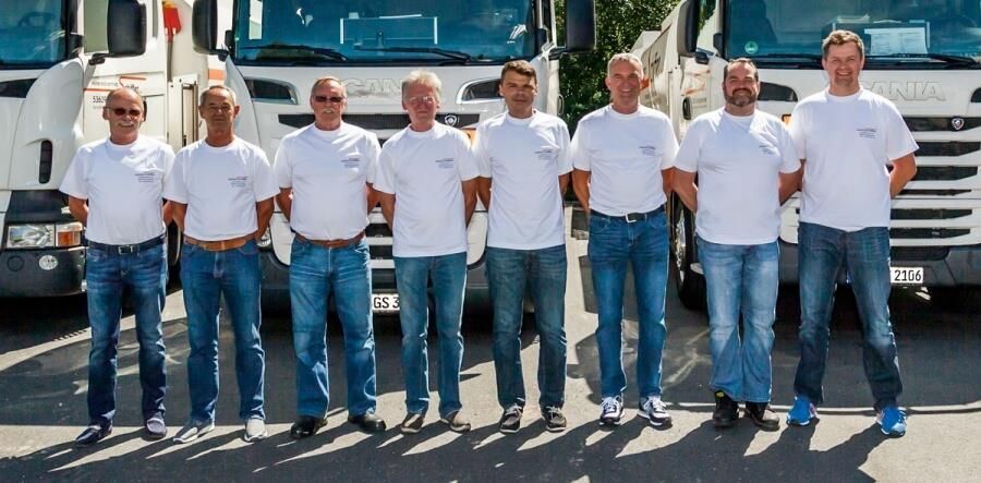 Eine Gruppe von Männern posiert für ein Foto vor Lastwagen