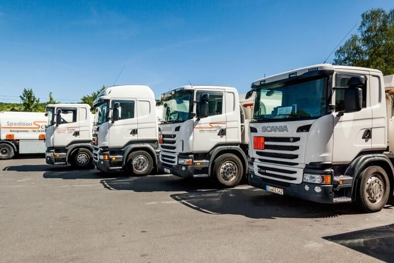Eine Reihe weißer Lastwagen stehen auf einem Parkplatz