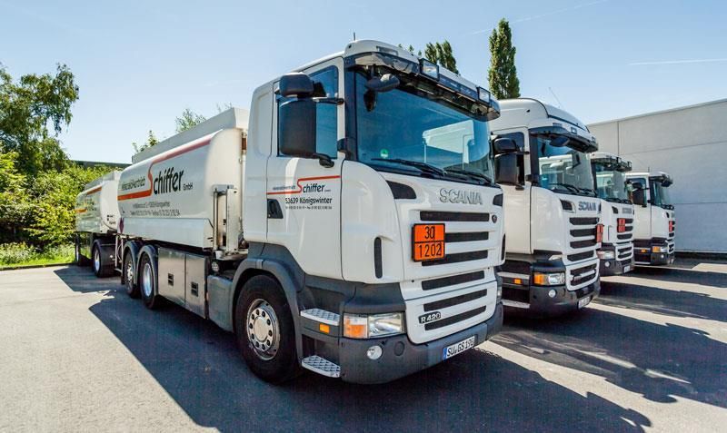 Auf einem Parkplatz steht eine Reihe weißer Lastwagen.
