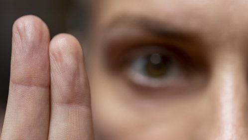 Gros plan sur une personne qui regarde par-dessus deux doigts