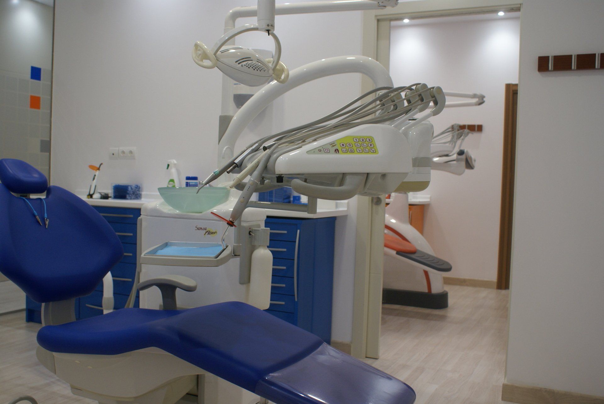 Consultorio dental con silla y equipo azul; paredes blancas.