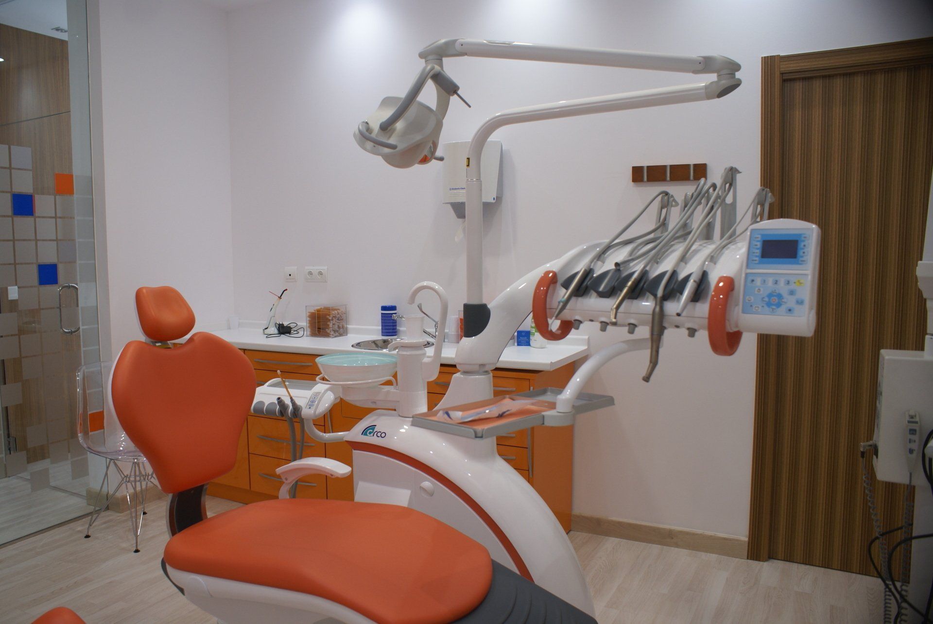 Sillón dental en una clínica moderna con detalles en naranja y equipamiento médico.
