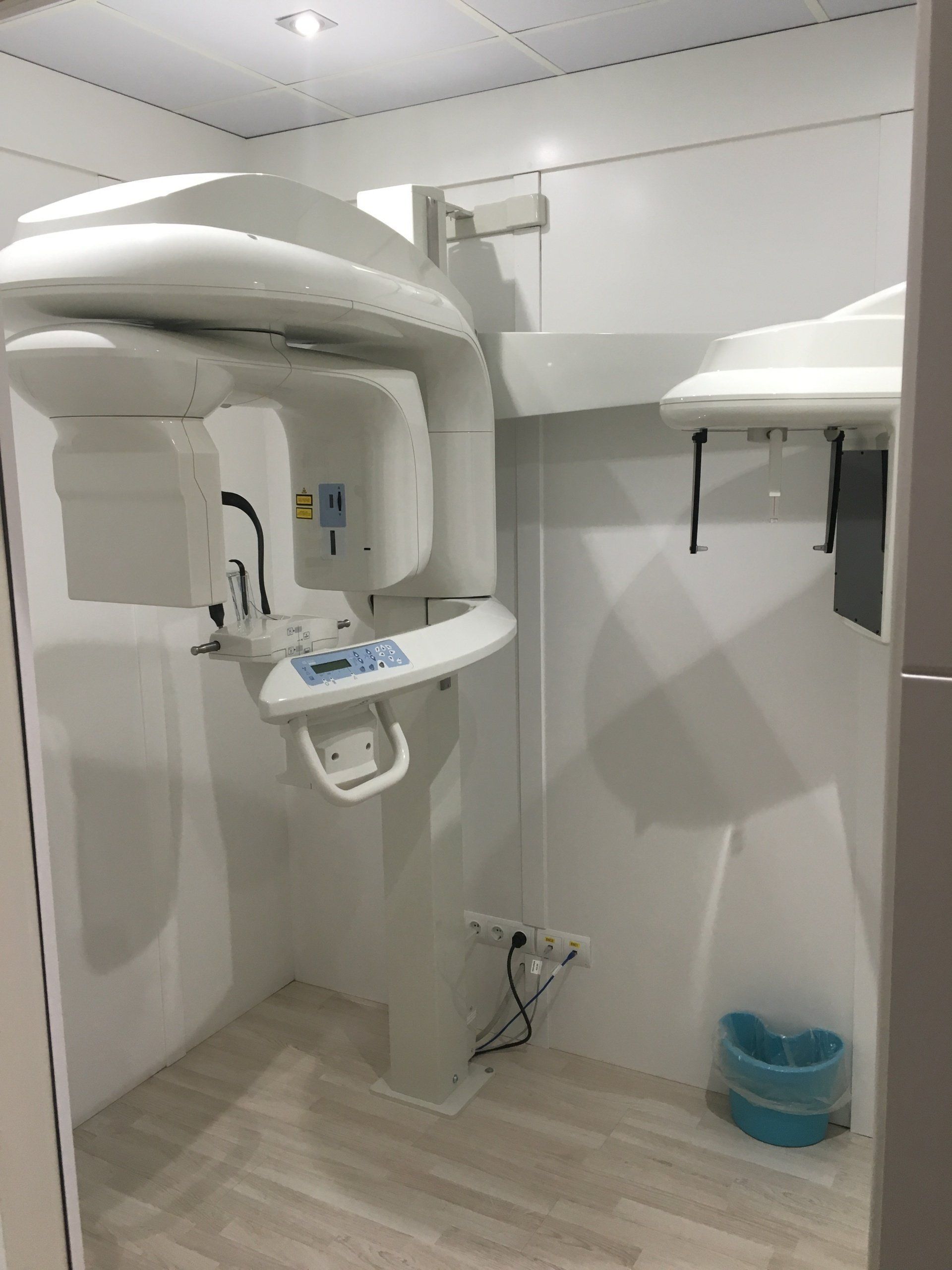 Máquina de rayos X panorámicos dentales en una sala blanca, lista para escanear los dientes de un paciente.