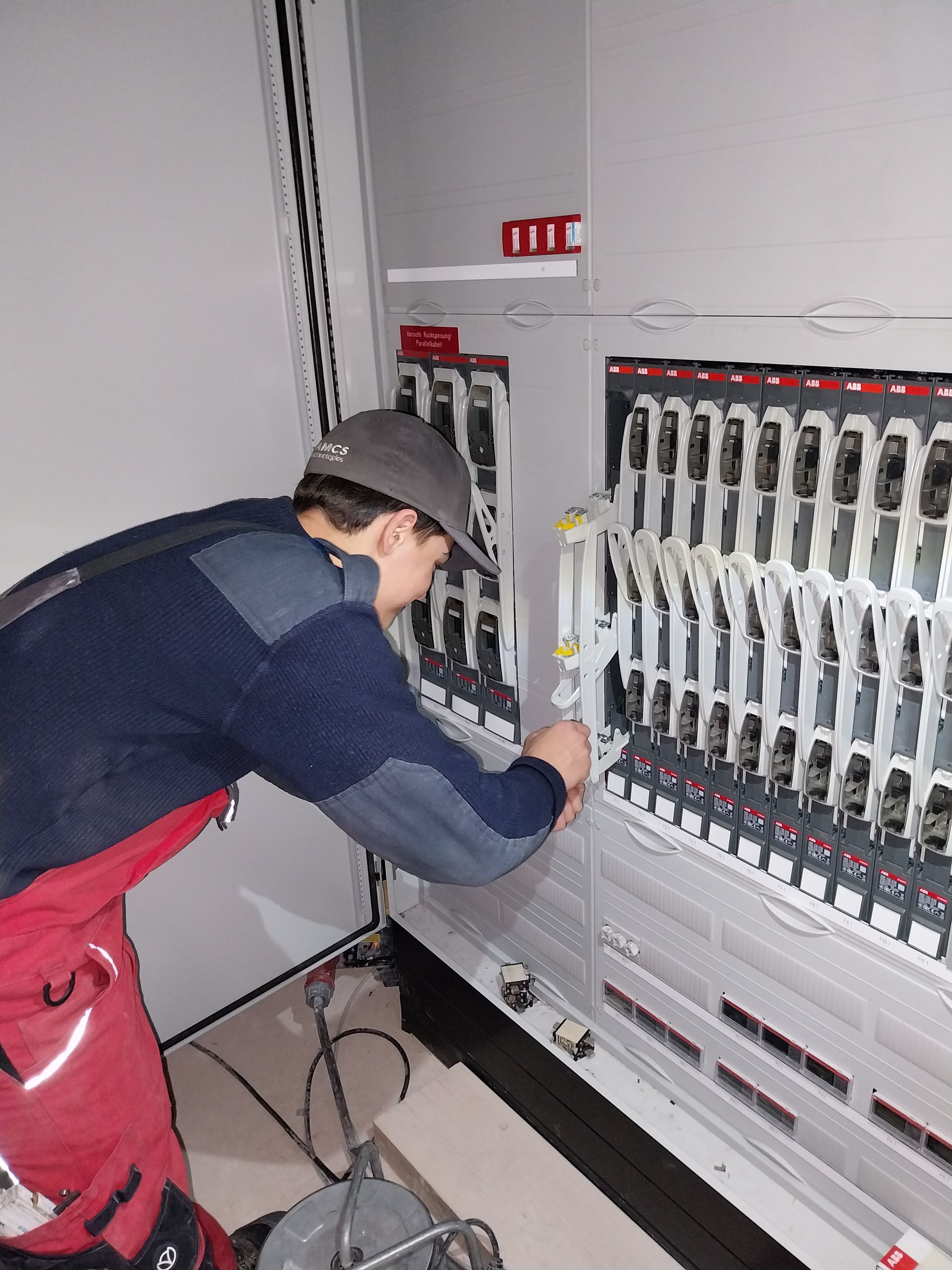 Elektrotechnik-Azubi an einem industriellen Stromkasten