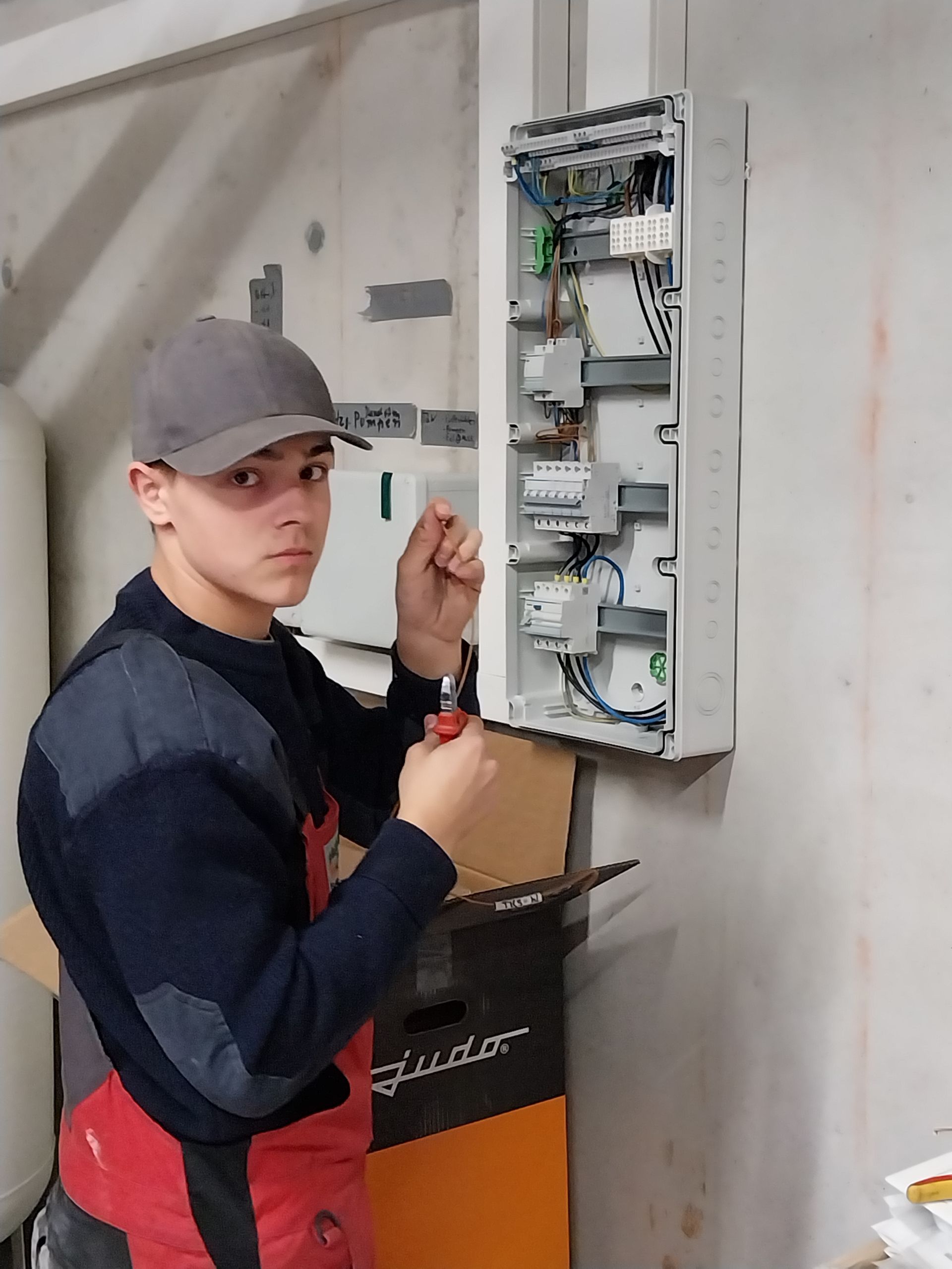 Elektrotechnik-Azubi an einem Stromkasten