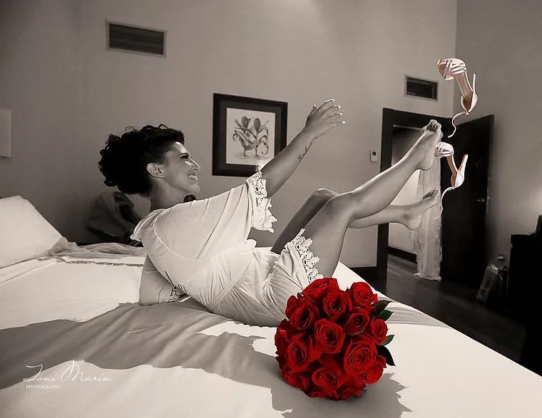 Una mujer está acostada en una cama con un ramo de rosas rojas.
