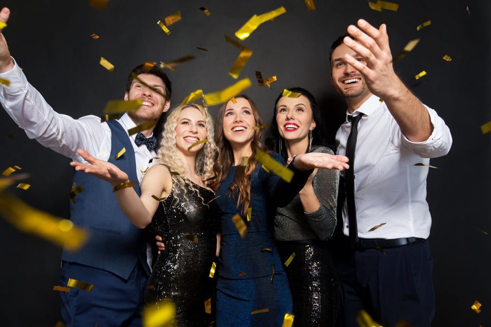 Un grupo de personas está lanzando confeti dorado al aire.