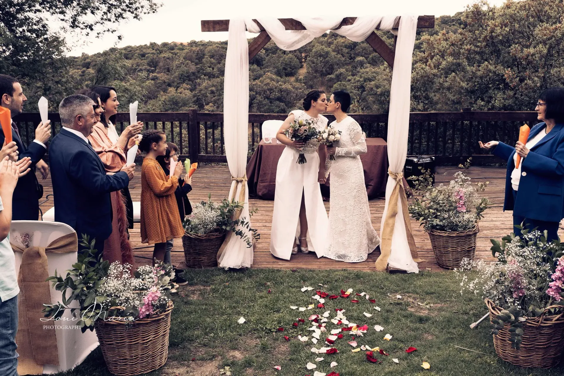 Dos mujeres se besan en una ceremonia de boda bajo un dosel.