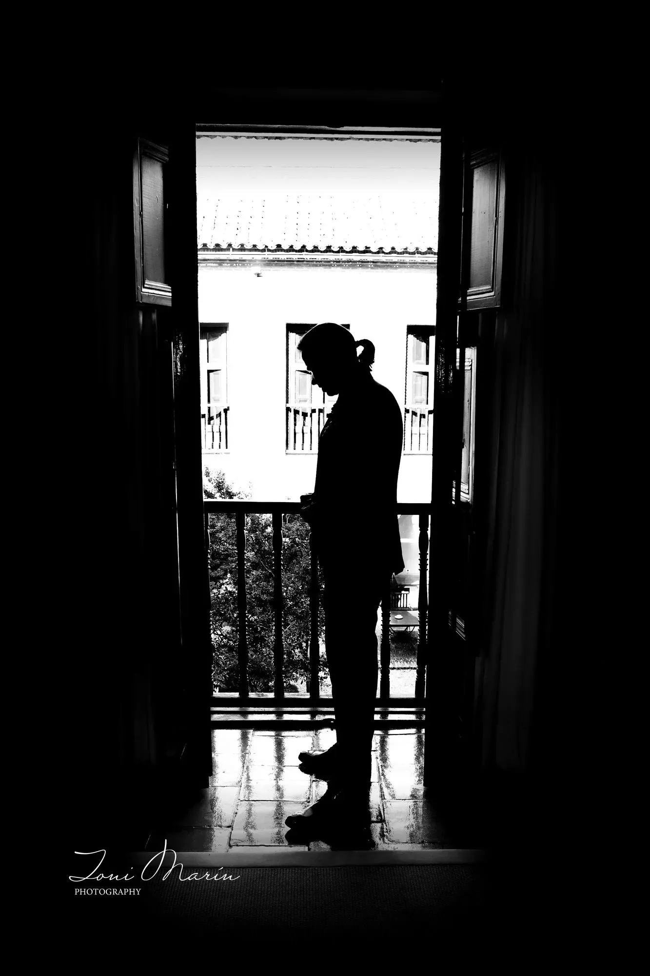 Una fotografía en blanco y negro de un hombre parado en un balcón.