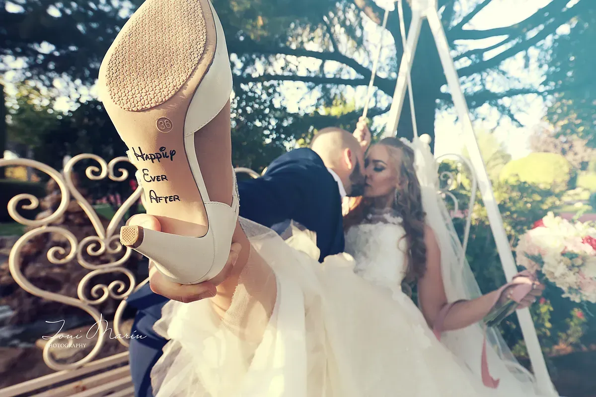 Una novia y un novio se besan en un columpio y el zapato de la novia tiene un tatuaje.
